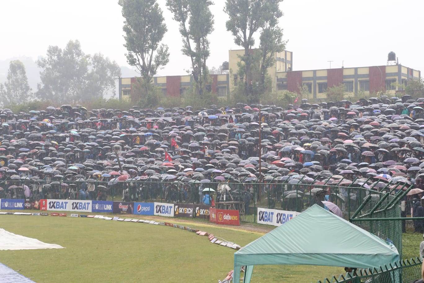 अझै रोकिएन वर्षा, छाता ओढेर दर्शक खेल हेर्न कुर्दै (फोटो फिचर)